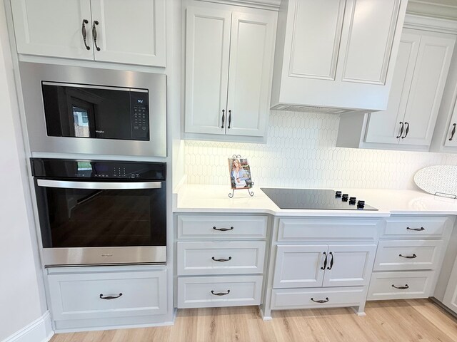 4965 Hatfield Cir, Hahira, GA 31632 - kitchen with stainless steel appliances, light wood finished floors, light countertops, white cabinetry, and backsplash