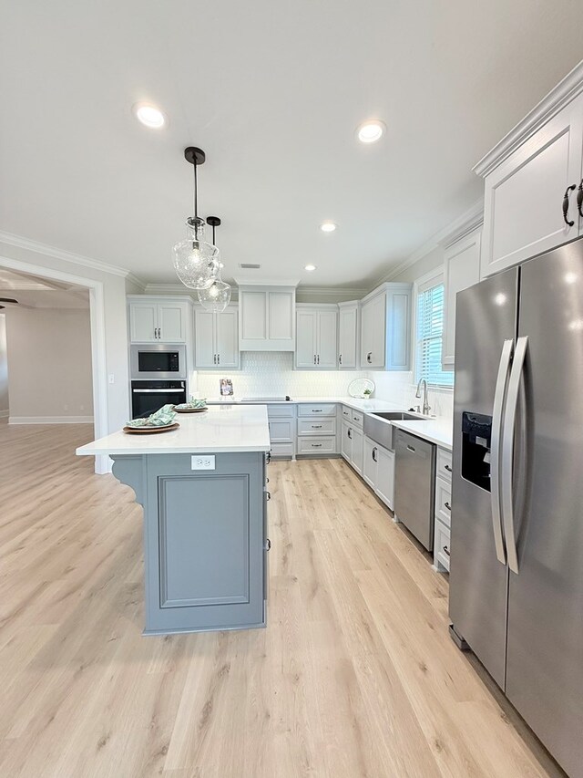 4965 Hatfield Cir, Hahira, GA 31632 - kitchen featuring appliances with stainless steel finishes, crown molding, light countertops, a sink, and a kitchen island