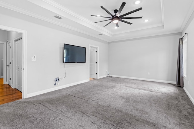 unfurnished living room with ornamental molding, a raised ceiling, ceiling fan, and carpet floors