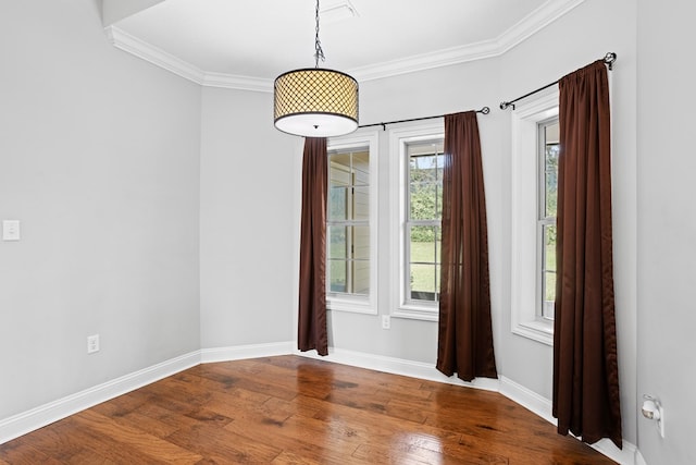 empty room featuring crown molding, baseboards, and wood finished floors