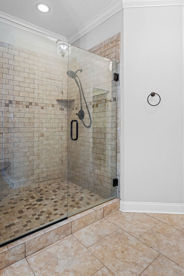 bathroom with a textured ceiling, ornamental molding, a shower stall, and baseboards