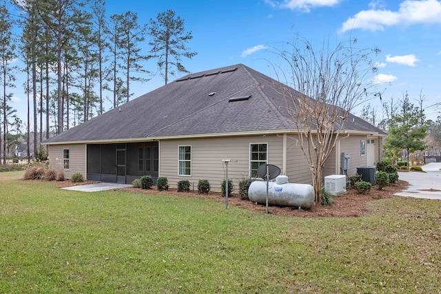 back of house with roof with shingles, central AC unit, a lawn, and a sunroom