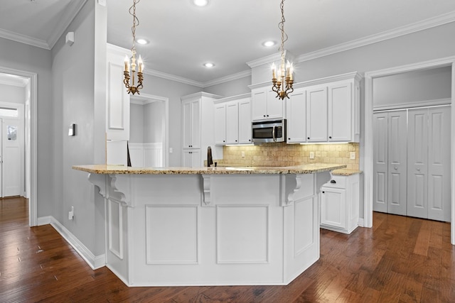 kitchen with white cabinets, stainless steel microwave, a breakfast bar area, and light stone countertops