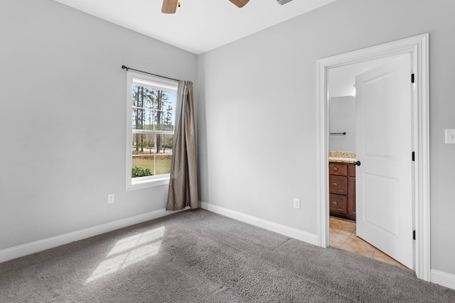 unfurnished bedroom with light colored carpet, ceiling fan, ensuite bath, and baseboards