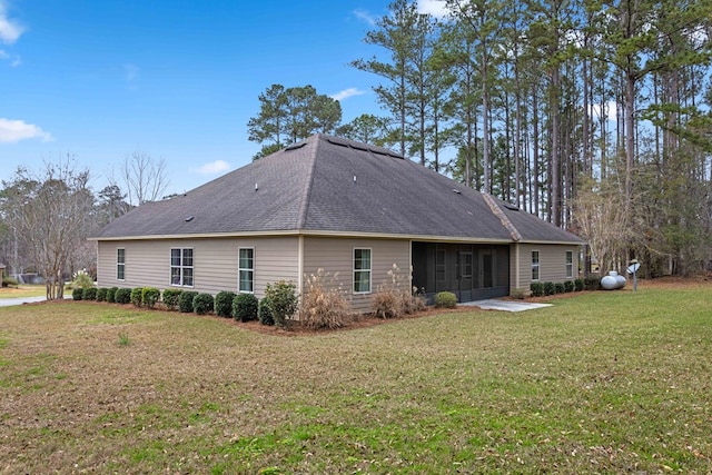 rear view of property featuring roof with shingles and a yard