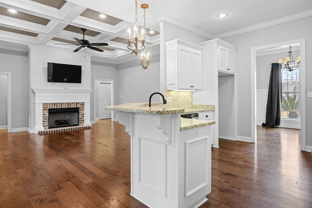 kitchen featuring white cabinets, light stone counters, a breakfast bar, a peninsula, and a fireplace