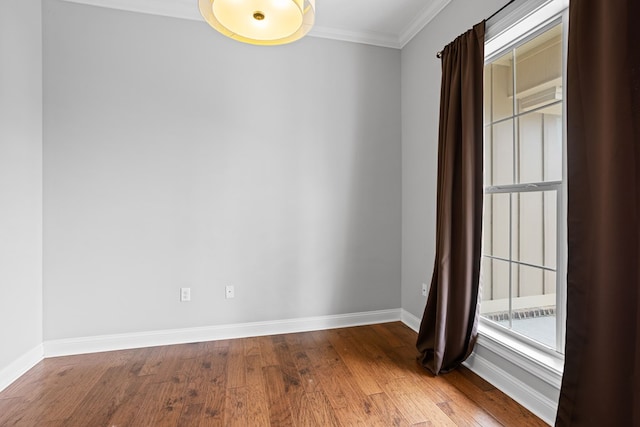 unfurnished room featuring ornamental molding, baseboards, and wood finished floors