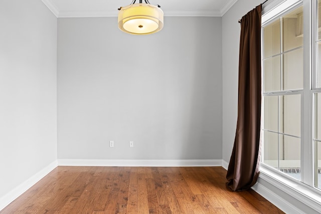 empty room with ornamental molding, baseboards, and wood finished floors