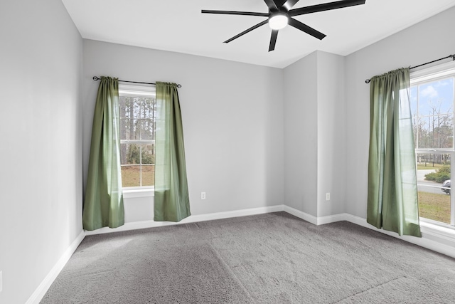 carpeted empty room featuring a ceiling fan and baseboards