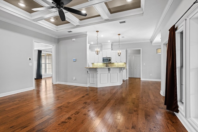 kitchen featuring dark wood-type flooring, a breakfast bar, ornamental molding, tasteful backsplash, and stainless steel microwave