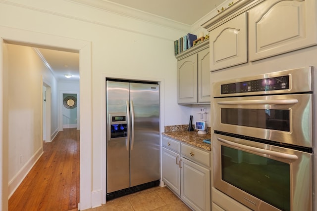 7552 Webb Rd, Hahira, GA 31632 - kitchen featuring appliances with stainless steel finishes, crown molding, dark stone counters, and light wood-style floors