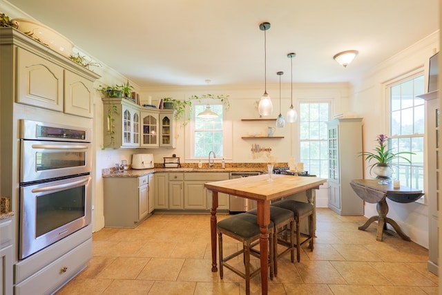 7552 Webb Rd, Hahira, GA 31632 - kitchen featuring appliances with stainless steel finishes, glass insert cabinets, hanging light fixtures, light tile patterned flooring, and ornamental molding