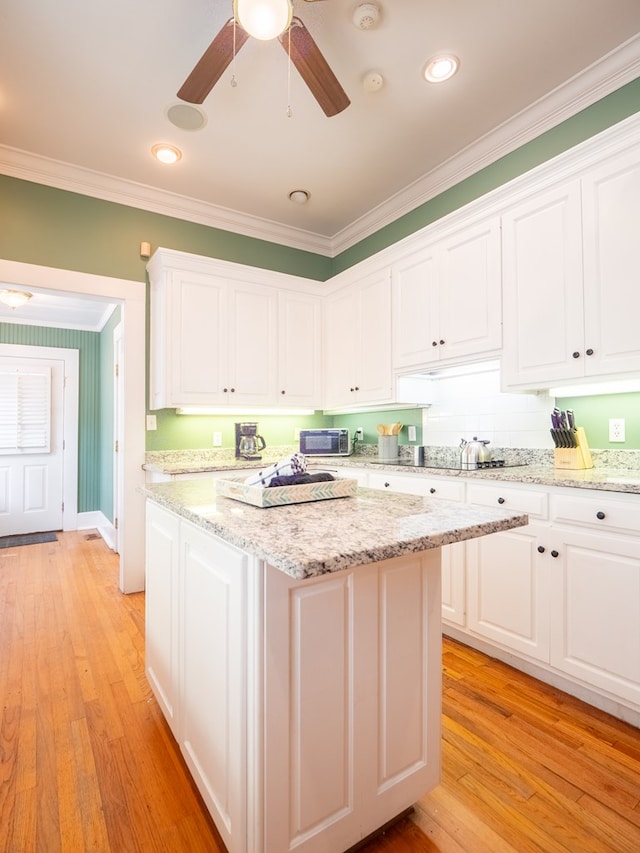 103 W Moore St, Valdosta, GA 31602 - kitchen with ornamental molding, white cabinetry, light wood-style flooring, a ceiling fan, and a center island