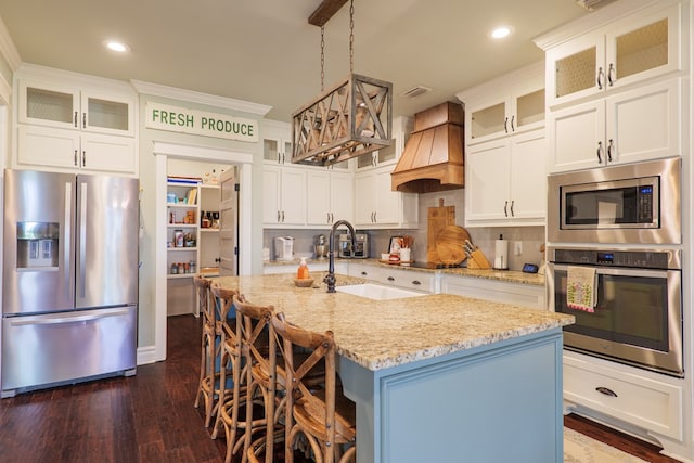 7351 Woodbend Trl, Hahira, GA 31632 - kitchen with stainless steel appliances, premium range hood, dark wood finished floors, light stone countertops, and an island with sink
