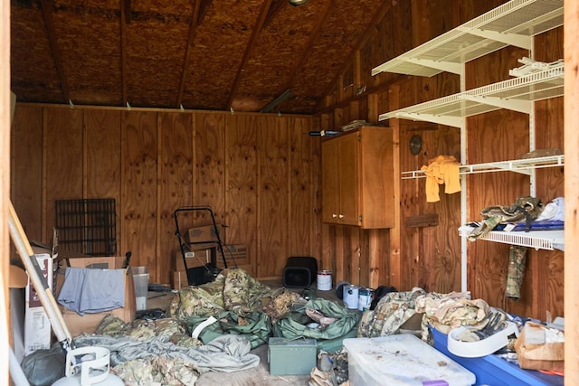 miscellaneous room featuring lofted ceiling and wooden walls