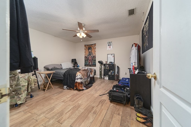 bedroom featuring a textured ceiling, light wood-type flooring, and ceiling fan