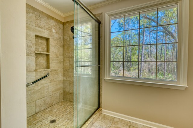 bathroom featuring tile patterned floors, a shower with shower door, a healthy amount of sunlight, and ornamental molding