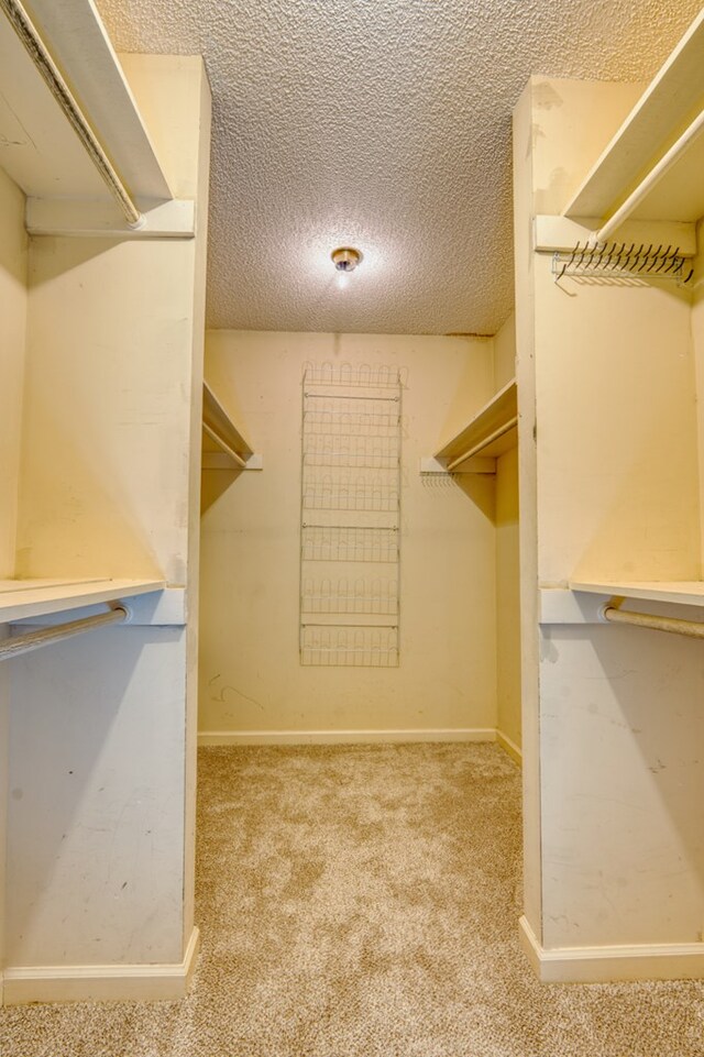 bedroom featuring a textured ceiling, light colored carpet, and ceiling fan