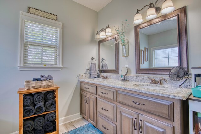 bathroom with double vanity, a sink, wood finished floors, and baseboards