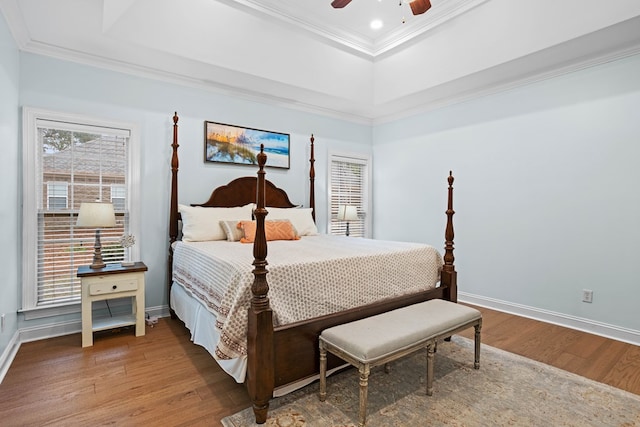 bedroom with ceiling fan, a raised ceiling, wood-type flooring, and ornamental molding