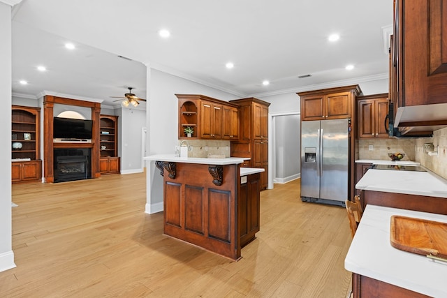 kitchen featuring a breakfast bar, ceiling fan, tasteful backsplash, a kitchen island, and stainless steel fridge with ice dispenser