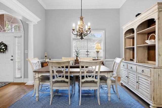 dining room with an inviting chandelier, dark hardwood / wood-style flooring, crown molding, and decorative columns