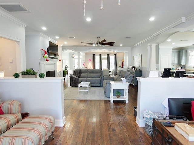 living room featuring ceiling fan, ornamental molding, and dark wood-type flooring