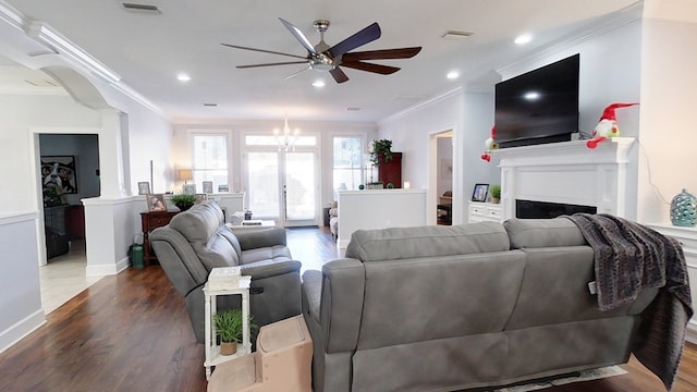 living room with dark hardwood / wood-style floors, crown molding, and ceiling fan with notable chandelier