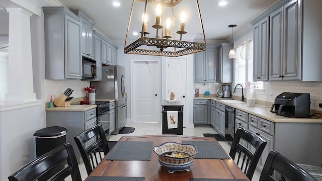 kitchen with gray cabinetry, black appliances, crown molding, sink, and hanging light fixtures