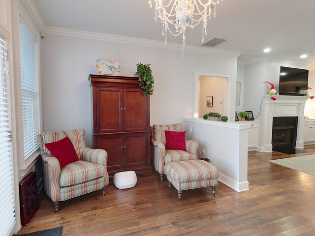 living area featuring dark hardwood / wood-style flooring, ornamental molding, and a notable chandelier