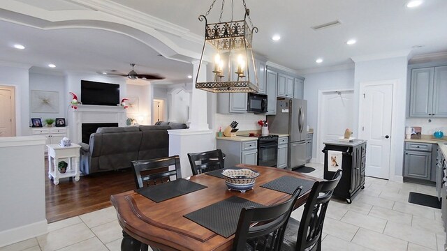 tiled dining space featuring ceiling fan and ornamental molding