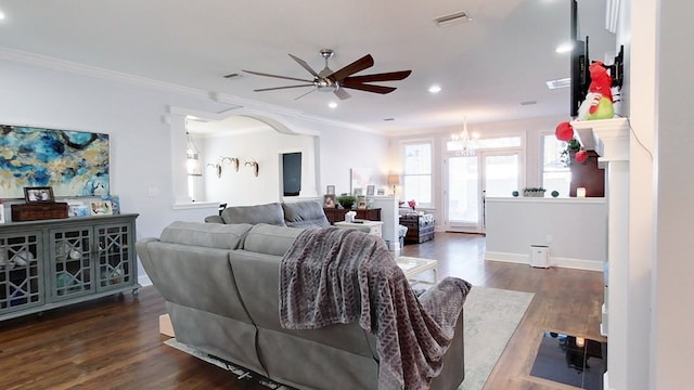 living room with ceiling fan with notable chandelier, ornamental molding, and dark wood-type flooring