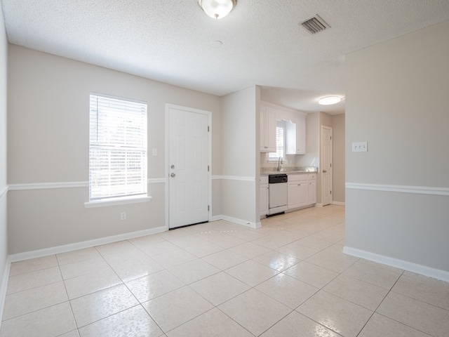 spare room featuring a textured ceiling, plenty of natural light, and light tile patterned flooring