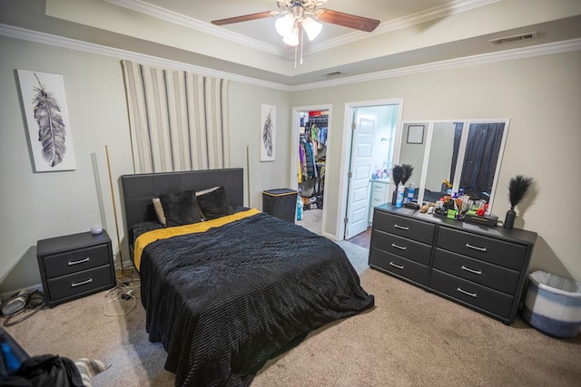 carpeted bedroom featuring ceiling fan, a closet, crown molding, and a tray ceiling