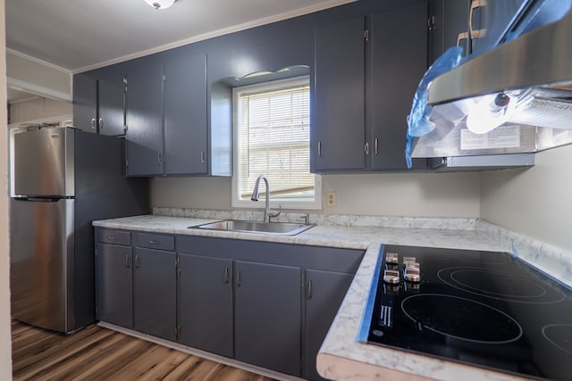 kitchen featuring stainless steel refrigerator, sink, dark wood-type flooring, black stovetop, and ornamental molding