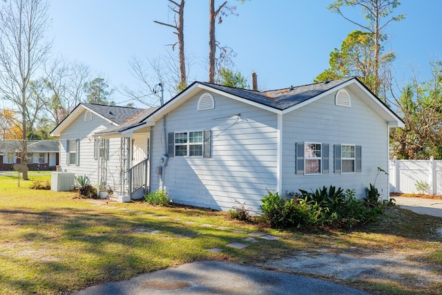 view of side of property with central AC unit and a lawn