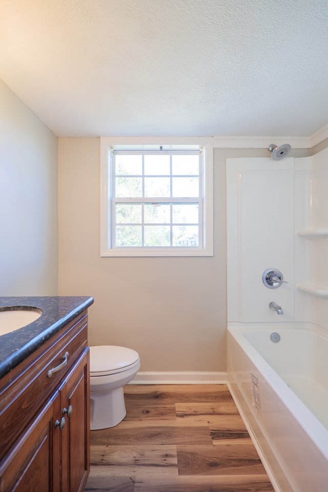 full bathroom featuring wood-type flooring, a textured ceiling,  shower combination, toilet, and vanity