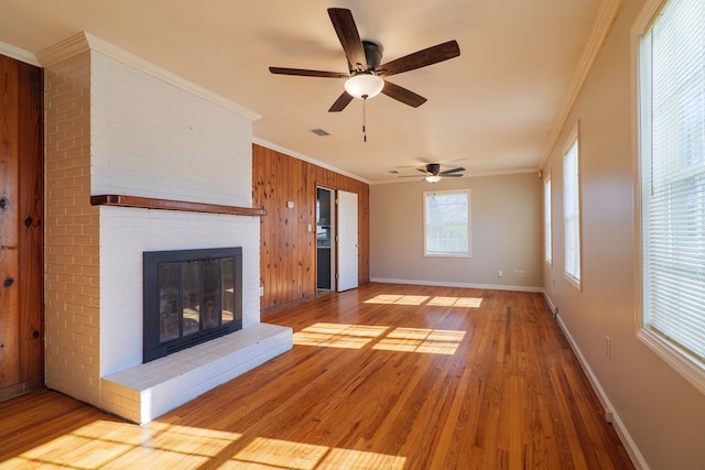 unfurnished living room with a fireplace, light hardwood / wood-style flooring, ornamental molding, and wood walls