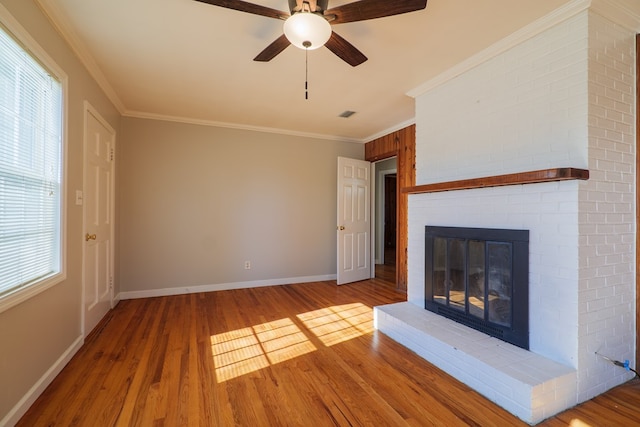 unfurnished living room with light wood-type flooring, a brick fireplace, ceiling fan, and crown molding