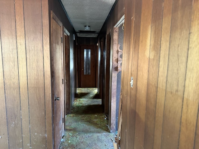 hall featuring wood walls and a textured ceiling