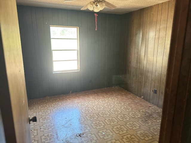 spare room featuring wooden walls and a textured ceiling