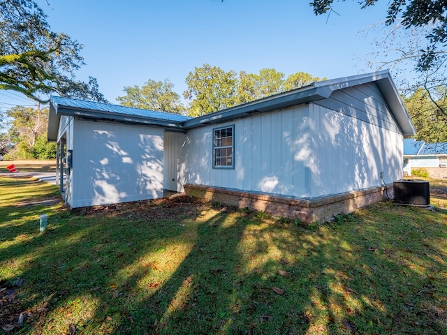 rear view of property featuring a lawn and cooling unit