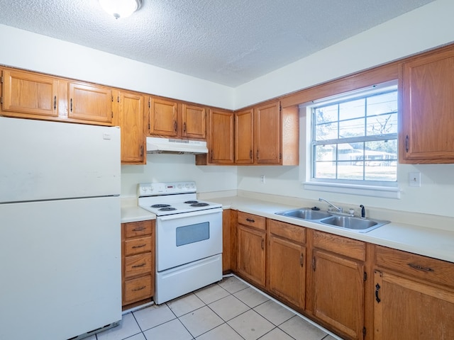 kitchen with light tile patterned flooring, a textured ceiling, white appliances, and sink