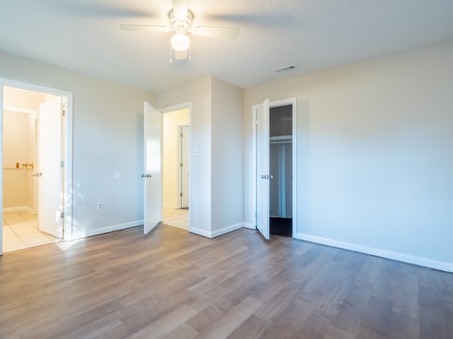 unfurnished bedroom with a textured ceiling, a closet, light hardwood / wood-style floors, and ceiling fan