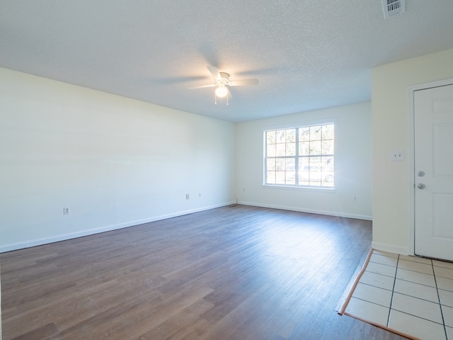 unfurnished room featuring ceiling fan, dark hardwood / wood-style flooring, and a textured ceiling