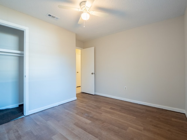 unfurnished bedroom featuring ceiling fan, wood-type flooring, a textured ceiling, and a closet