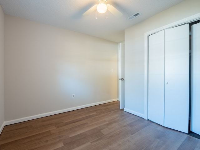 unfurnished bedroom featuring ceiling fan, a closet, a textured ceiling, and hardwood / wood-style flooring