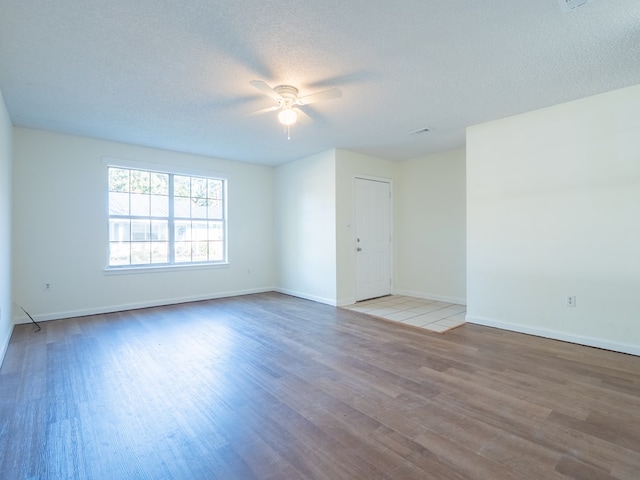 empty room featuring ceiling fan, wood-type flooring, and a textured ceiling