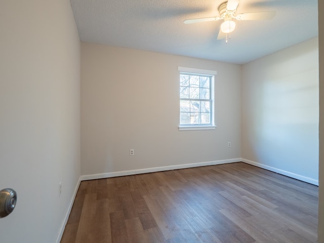 empty room with ceiling fan, wood-type flooring, and a textured ceiling