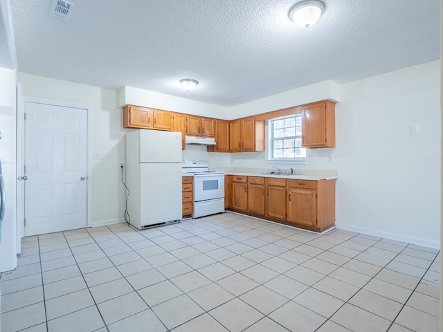 kitchen with a textured ceiling, sink, light tile patterned floors, and white appliances